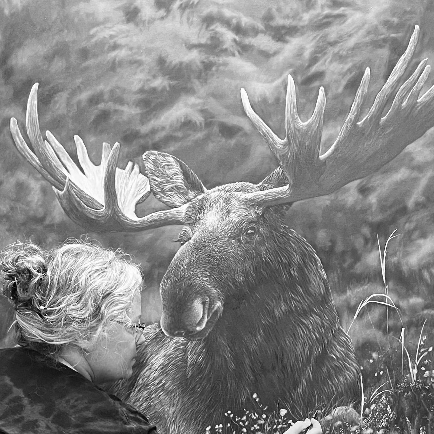 A black and white artwork depicting a large moose with massive antlers lying in a forest while a Karen paints the landscape in the foreground.