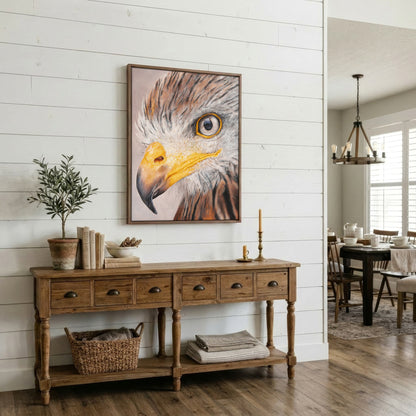 A framed vertical canvas print of an eagle's face hangs on a white shiplap wall above a rustic wooden console table in a bright, modern farmhouse dining room.