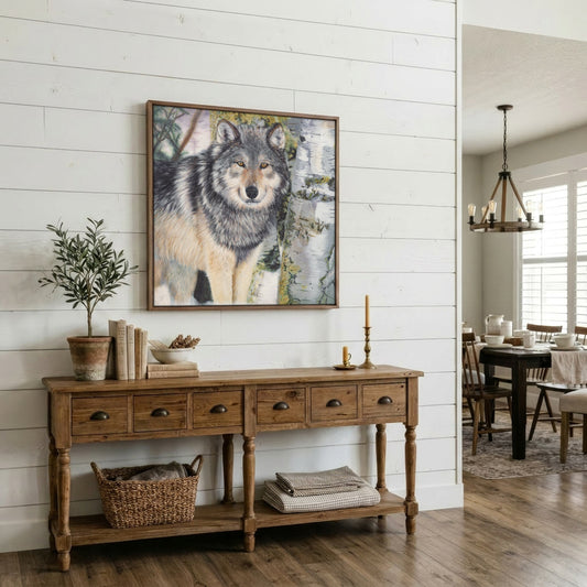 A framed wolf art print hangs on a white shiplap wall above a rustic wooden console table in a bright, modern dining room.