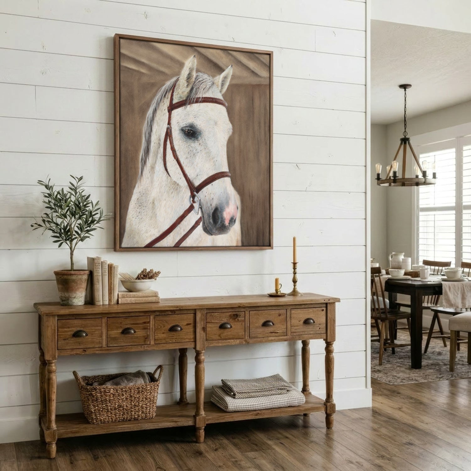 A framed canvas print of a white horse's head with brown reins, displayed on a white shiplap wall above a rustic wooden console table in a bright, modern farmhouse-style room.