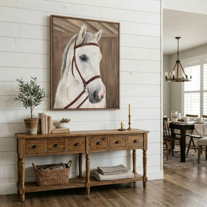 A framed canvas print of a white horse's head with brown reins, displayed on a white shiplap wall above a rustic wooden console table in a bright, modern farmhouse-style room.