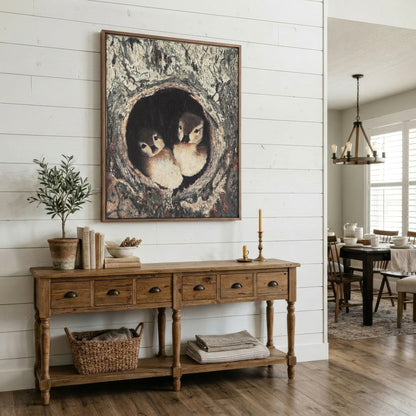A large framed art print depicting two baby ducks in a tree hollow, styled on a white shiplap wall above a rustic wooden console table in a bright, modern farmhouse dining room.